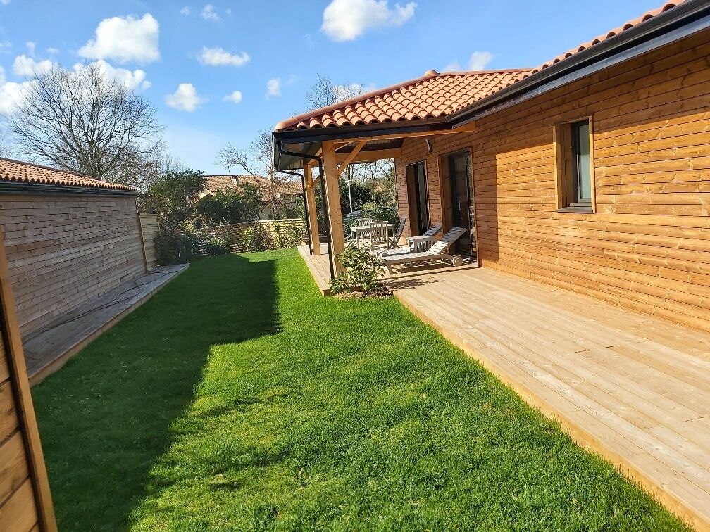A wooden cabin with a covered patio and a well-maintained lawn.