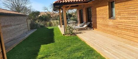 A wooden cabin with a covered patio and a well-maintained lawn.
