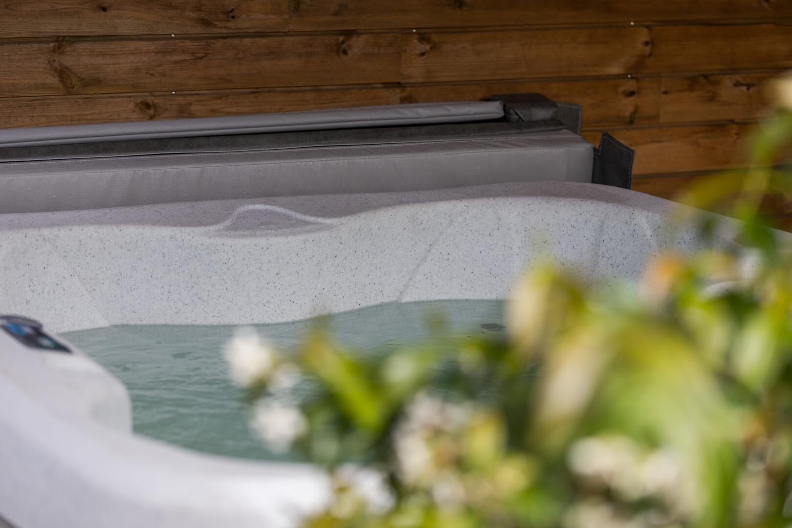 A hot tub with a wooden wall in the background.