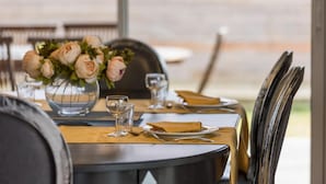 Una mesa de comedor dispuesta con platos, cubiertos y copas de vino, con un jarrón de flores en el centro.