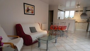 A living room with a glass coffee table, a sofa, and a dining table with chairs.