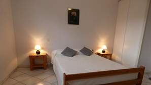 A neatly arranged bedroom with a wooden bed, two bedside tables with lamps, and a framed picture on the wall.