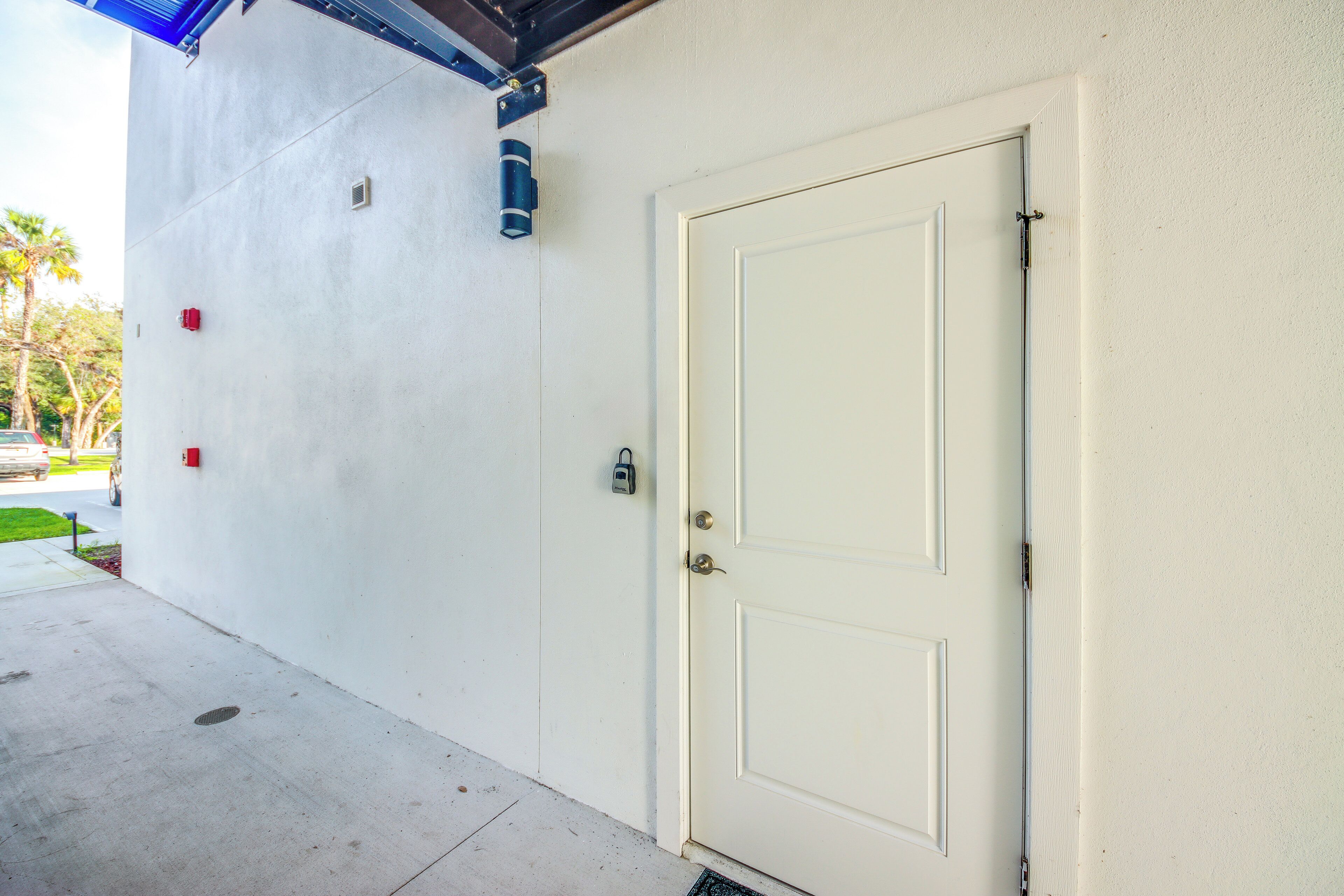 A white door with a keyhole and a lock, a small red mailbox, and a blue fire extinguisher mounted on the wall.