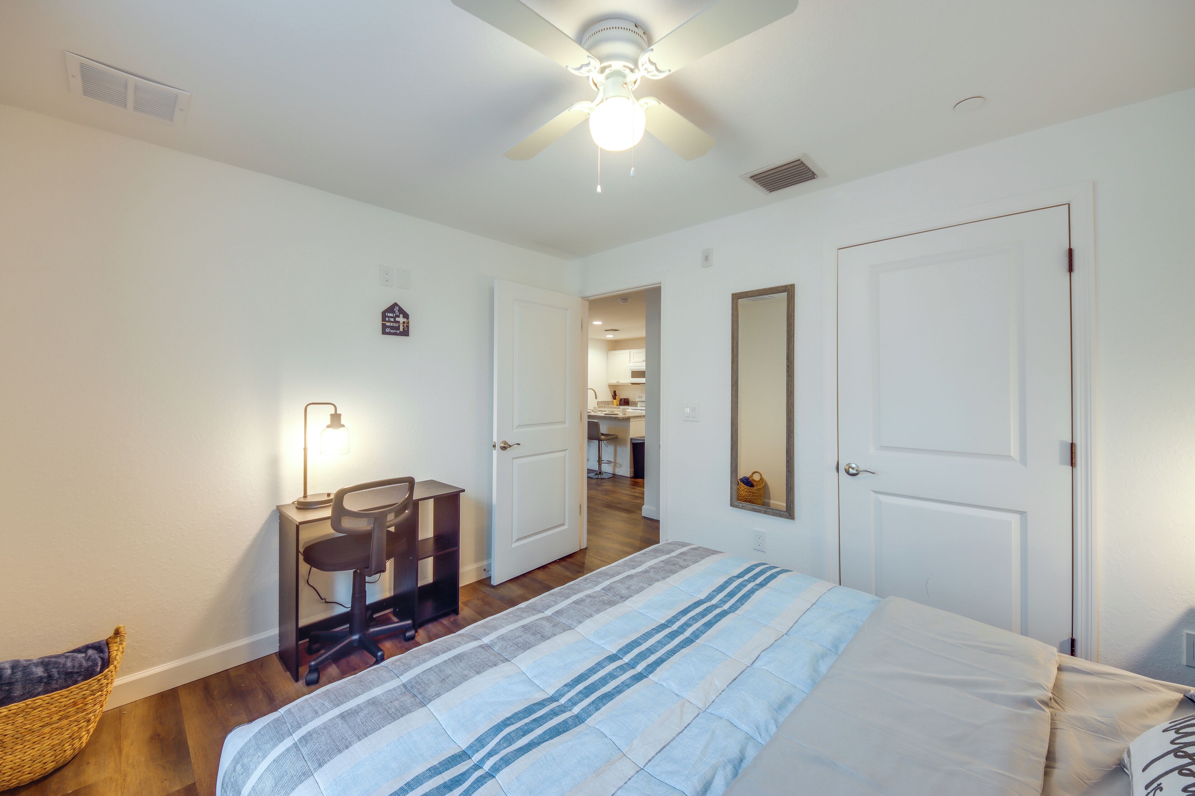 Une chambre à coucher comprenant un lit, un bureau, une chaise et un ventilateur de plafond.