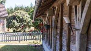 A wooden building with a white picket fence and a garden with red flowers. - Vieux Chêne - Vert - Gîte (VERT)