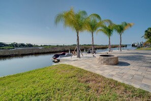 A waterfront park with palm trees, a boat dock, and a fire pit. - Luxe Spring Hill Home w/ Patio & Dock! (Spring Hill)