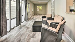 Una habitación amplia con un gran ventanal corredera, muebles de mimbre y vistas al exterior.