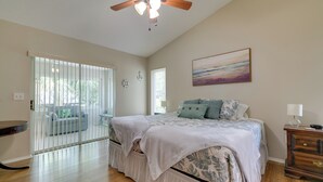 A bedroom with a bed, a ceiling fan, a painting, and a view through a sliding glass door. - Canal-front Retreat in Crystal River! (Crystal River)