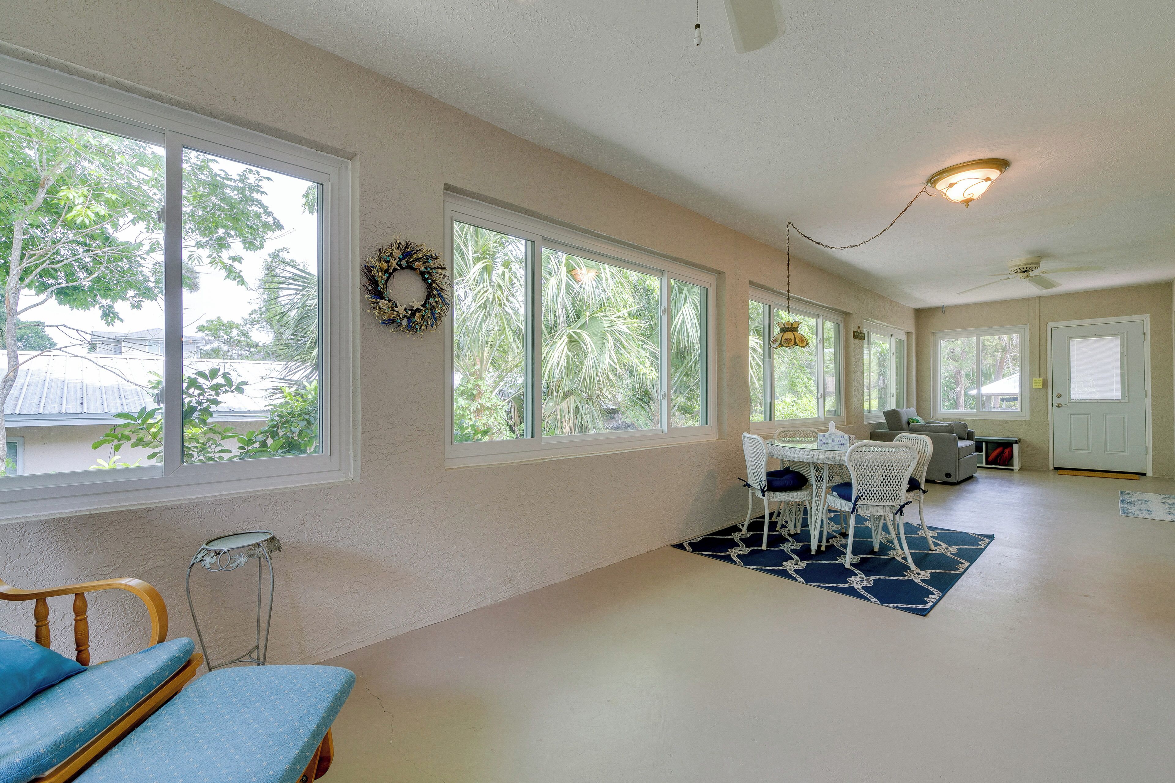 A spacious room with large windows, a dining area with a table and chairs, a ceiling fan, and a light fixture.