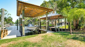 A dock with a covered area, a boat, and a small building with outdoor seating. - Canal-front Retreat in Crystal River! (Crystal River)