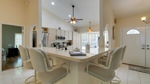 A spacious kitchen with a central island, white cabinetry, and a ceiling fan. - Canal-front Retreat in Crystal River! (Crystal River)