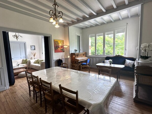 Una habitación amplia con una mesa de comedor, sillas, un piano y un sofá.