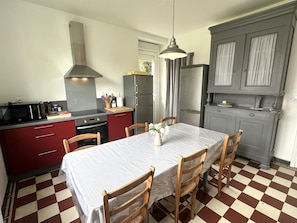 Una cocina compacta con mesa, sillas, microondas, horno y refrigerador.
