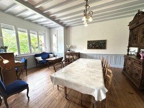 Un comedor con una mesa grande, sillas de madera, un sof á azul y una araña.