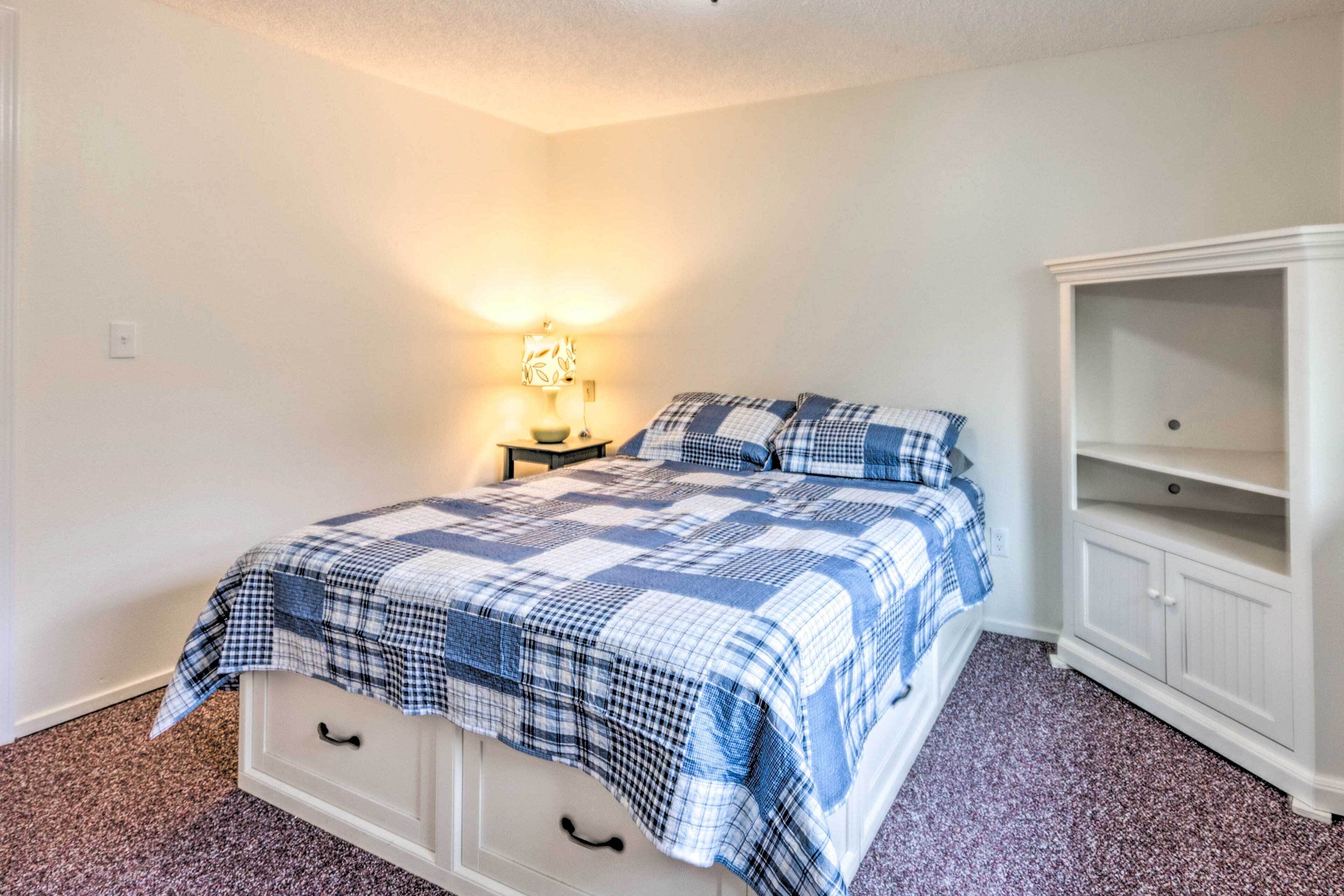 A bedroom with a bed, a nightstand, a lamp, and a white wardrobe.