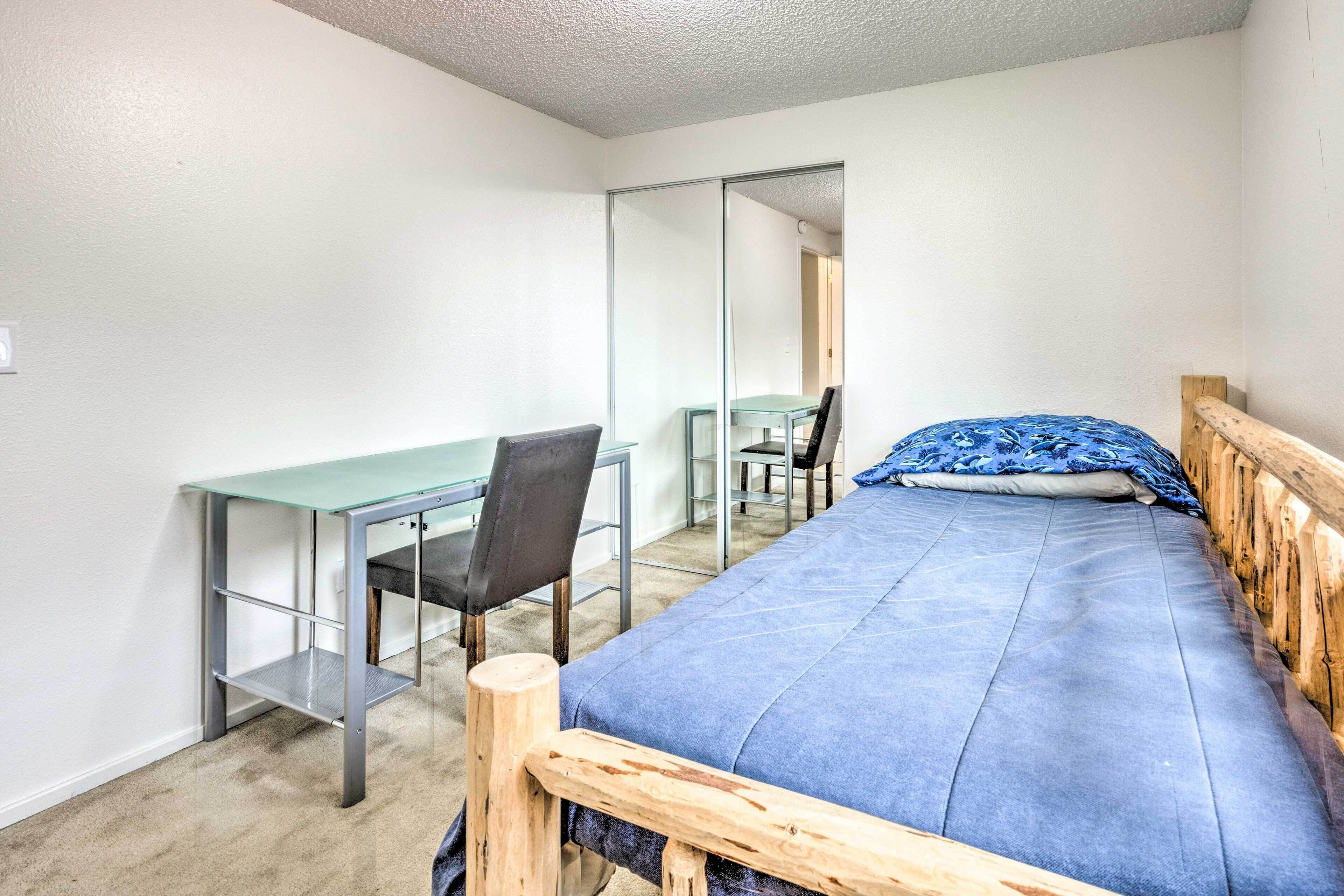 A bedroom with a bed, a desk, and a chair.