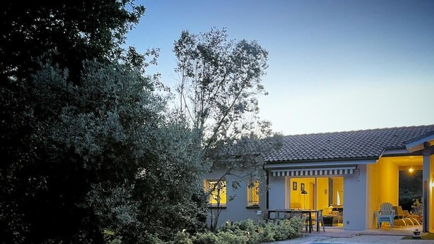 Una casa moderna con piscina, rodeada de abundante vegetación.