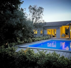 Ein modernes Haus mit Swimmingpool, umgeben von üppiger Vegetation.