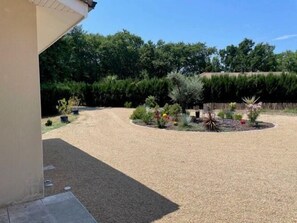 A gravel driveway leading to a landscaped garden area with various plants and shrubs.