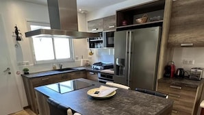 Una cocina moderna con una isla central, electrodomésticos de acero inoxidable y un amplio ventanal que proporciona luz natural.
