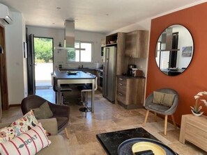 A modern kitchen with a dining area, a sofa, and a chair.