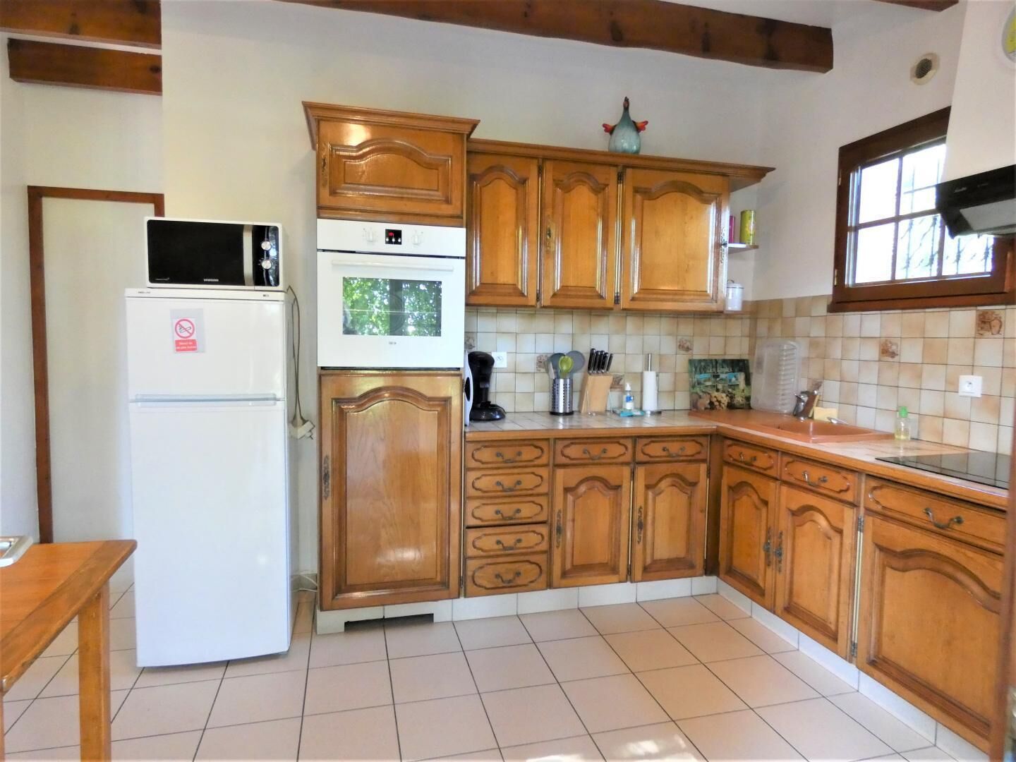 Une cuisine avec des meubles de rangement en bois, un réfrigérateur blanc, un four à micro-ondes et une cuisinière.