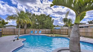 A swimming pool with a wooden fence, palm trees, and a clear blue sky. - Merritt Island Oasis w/ Pool ~ 7 Mi to Beach! (Merritt Island)