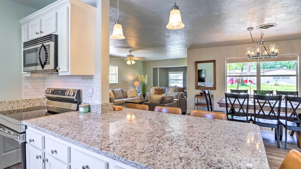 A kitchen with granite countertops, white cabinetry, a built-in microwave, and a stove. - Merritt Island Oasis w/ Pool ~ 7 Mi to Beach! (Merritt Island)