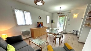 Ein modernes Wohnzimmer mit einer Couch, Sesseln, einem Glastisch und einem Essbereich mit Tisch und Stühlen.