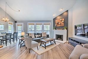 A spacious living room with a fireplace, a dining area, and a TV mounted on the wall.