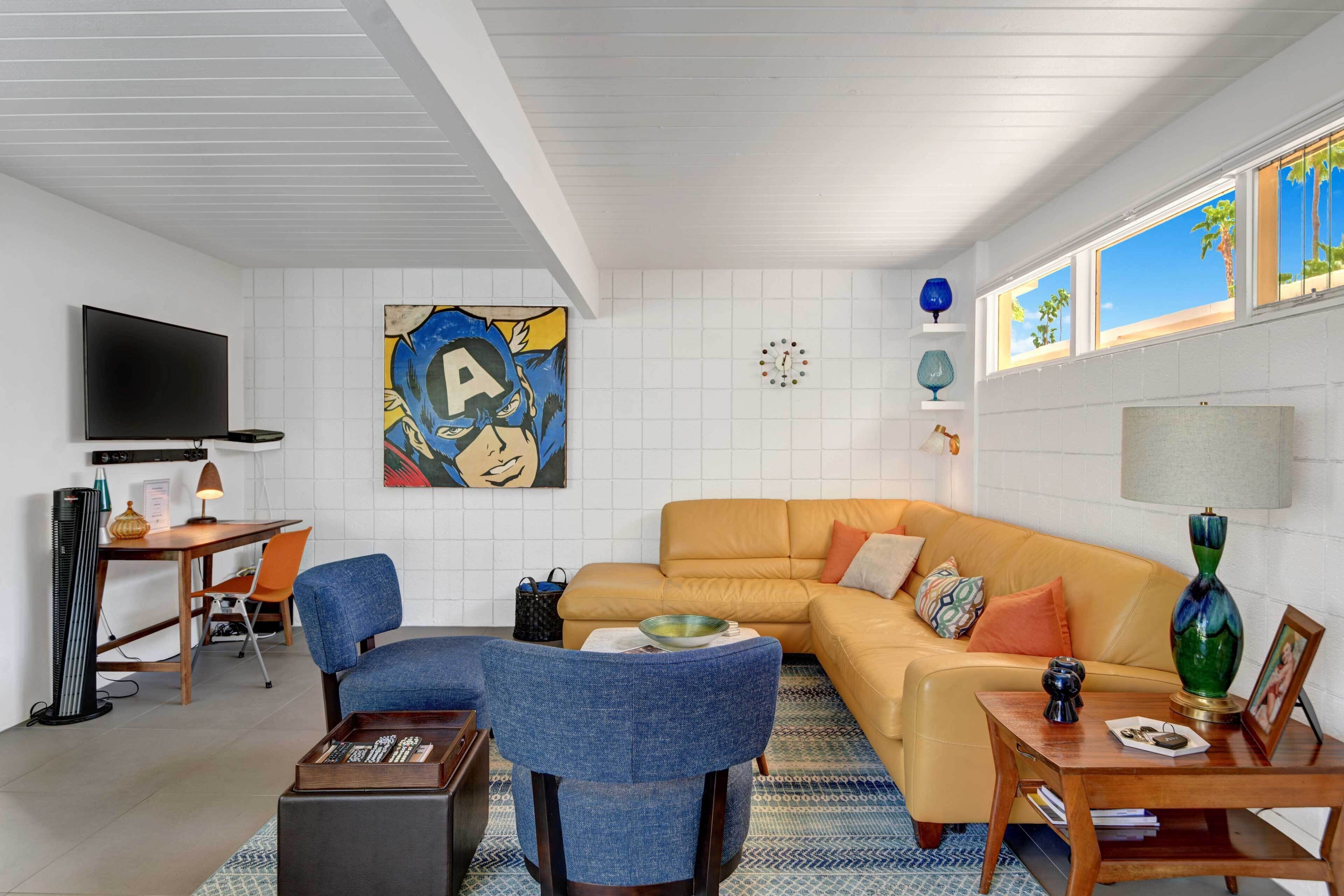A modern living room with a sofa, chairs, a coffee table, a TV, and artwork on the walls.