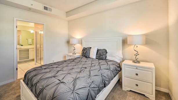 A bedroom with a large bed, two bedside tables with lamps, a white headboard, and a door leading to a bathroom. - Resort Getaway w/ Patio: 6 Mi to Disney Parks! (Kissimmee)