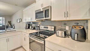 A modern kitchen with white cabinets, a stainless steel microwave, a built-in oven, a toaster, and an air fryer. - Resort Getaway w/ Patio: 6 Mi to Disney Parks! (Kissimmee)