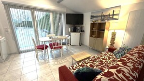 Un salon comprenant un canapé, une table basse, un téléviseur et un coin repas avec une table et des chaises.