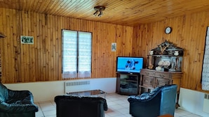 A wooden-paneled room with a television, two leather sofas, a small table, and a decorative cabinet.