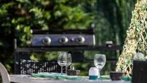 A table set outdoors with a grill in the background.