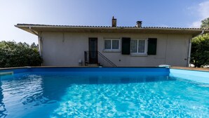 A house with a swimming pool, a small porch, and a door with a window above it.