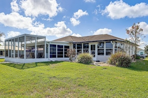 A modern house with a glass-enclosed porch, a well-maintained lawn, and a clear blue sky.