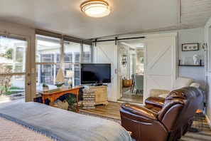 Una sala de estar acogedora con un televisor grande, un sillón de cuero y un aparador de madera con un letrero.