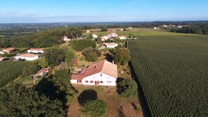An aerial view of a rural area with a large field, several houses, and a prominent white building with a red door.