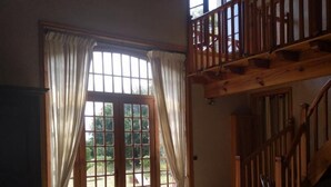 A cozy room with a sofa, chairs, a dining table, and a staircase.
