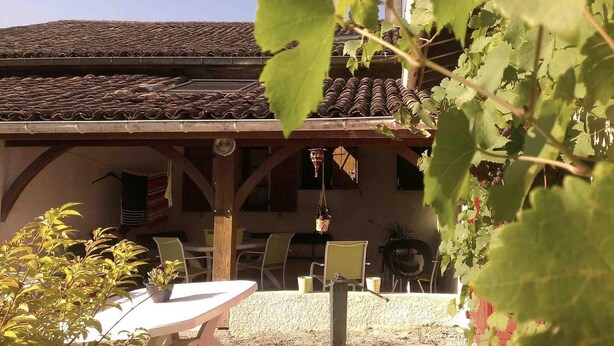A building with a tiled roof and a covered patio area with chairs and tables.
