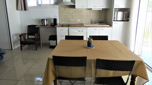 A compact kitchen with white cabinets, a tiled backsplash, a sink, and a window. - Les Palombières - SOUSTONS (SOUSTONS)