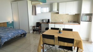 A compact room with a bed, a small dining table with chairs, a kitchenette, and a window. - Les Palombières - SOUSTONS (SOUSTONS)
