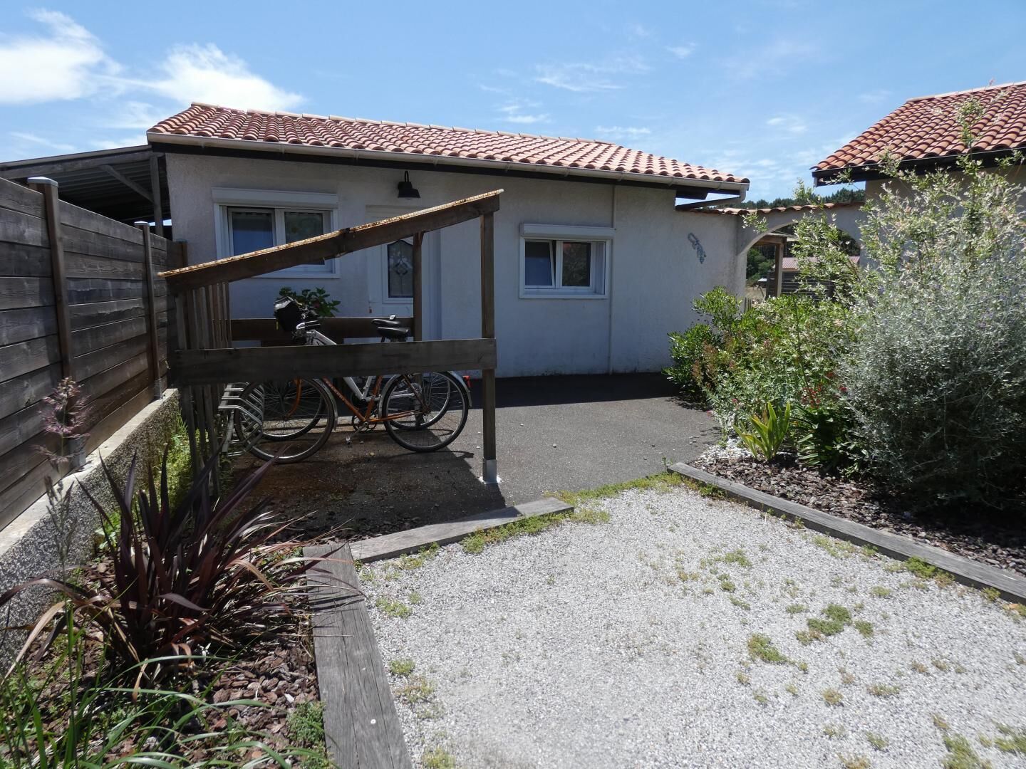 A residential property with a covered patio, a bicycle, and a garden area.