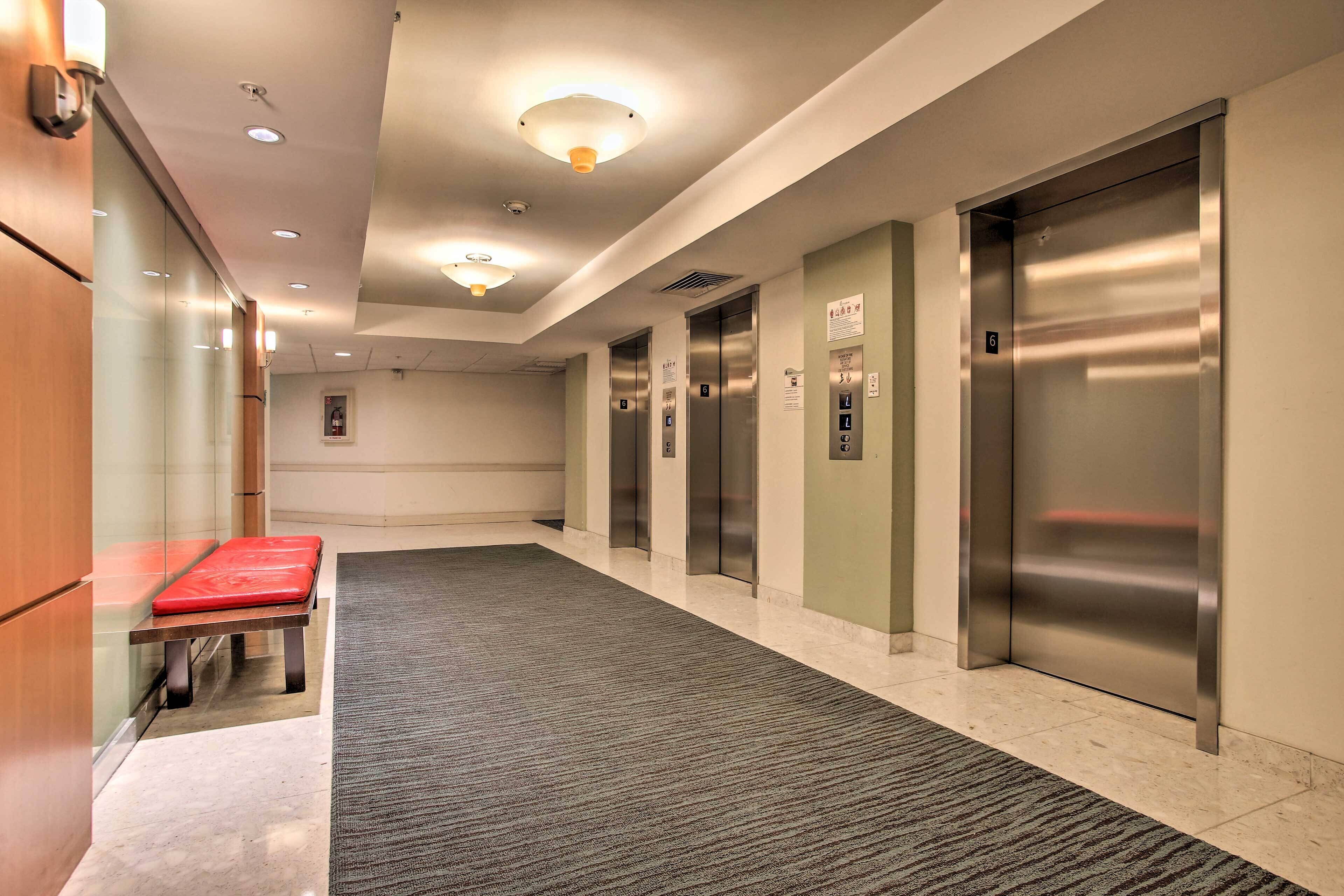 A hotel lobby with a carpeted floor, a bench, and an elevator.