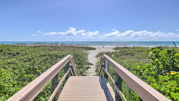 A wooden boardwalk leading to a beach with a clear sky. - 'the Palms' Cocoa Beach Condo: Walk to Beach! (Cocoa Beach)