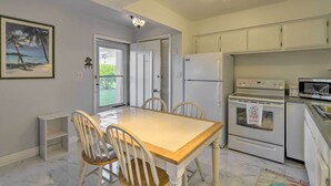 A kitchen with white cabinets, a wooden dining table, and chairs. - 'the Palms' Cocoa Beach Condo: Walk to Beach! (Cocoa Beach)