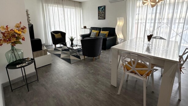Ein modernes Wohnzimmer mit Essbereich, ausgestattet mit einer Sofagarnitur, einem Couchtisch und einem Esstisch mit Stühlen.