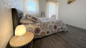 Ein Schlafzimmer mit einem Bett, einer Nachttischlampe, einem Sessel und einer Pendelleuchte.